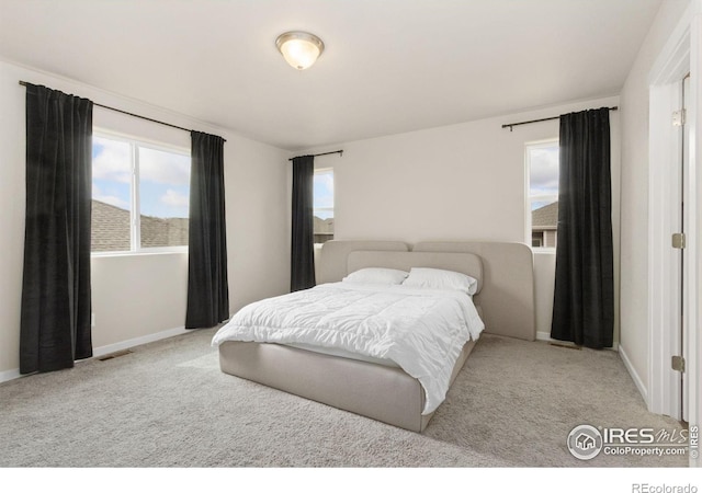 carpeted bedroom featuring baseboards, multiple windows, and visible vents
