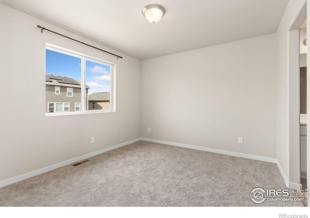 carpeted spare room featuring baseboards and visible vents
