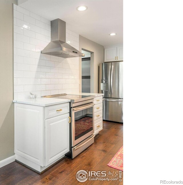kitchen with dark wood-style floors, recessed lighting, light countertops, wall chimney exhaust hood, and appliances with stainless steel finishes
