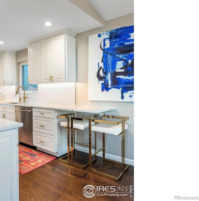 kitchen with tasteful backsplash, stainless steel dishwasher, dark wood finished floors, light countertops, and white cabinets