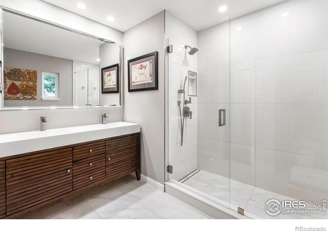bathroom featuring double vanity, a stall shower, a sink, and marble finish floor
