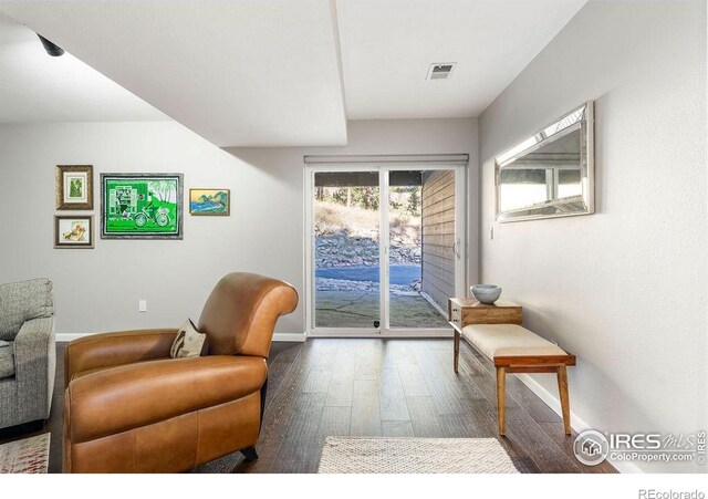 living area featuring visible vents, baseboards, and hardwood / wood-style flooring