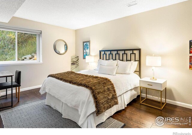 bedroom with baseboards, wood finished floors, and visible vents
