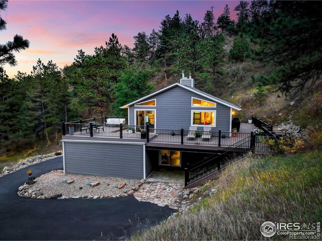 back of house with a wooden deck and a chimney