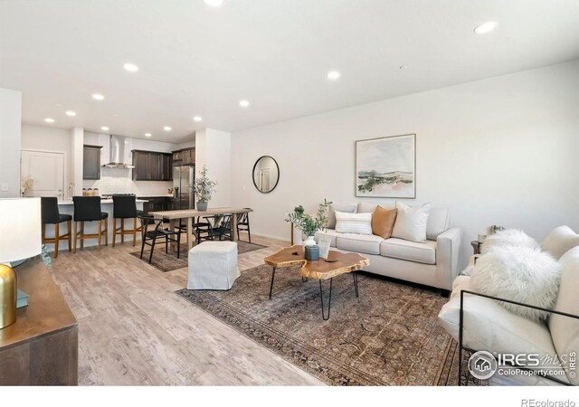 living area featuring light wood-type flooring, recessed lighting, and baseboards