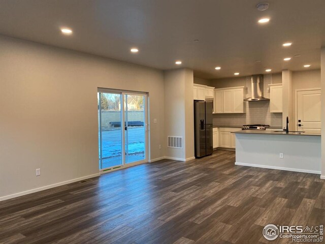kitchen featuring wall chimney range hood, dark wood-style flooring, a sink, fridge with ice dispenser, and visible vents