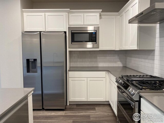 kitchen featuring decorative backsplash, appliances with stainless steel finishes, white cabinets, and wall chimney range hood