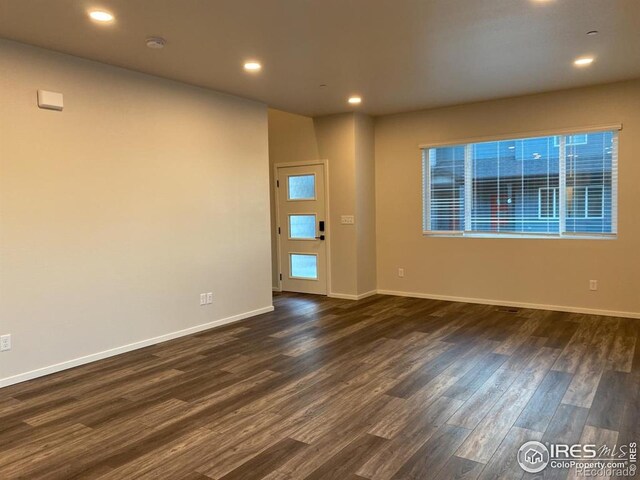 unfurnished room featuring recessed lighting, baseboards, and dark wood-type flooring
