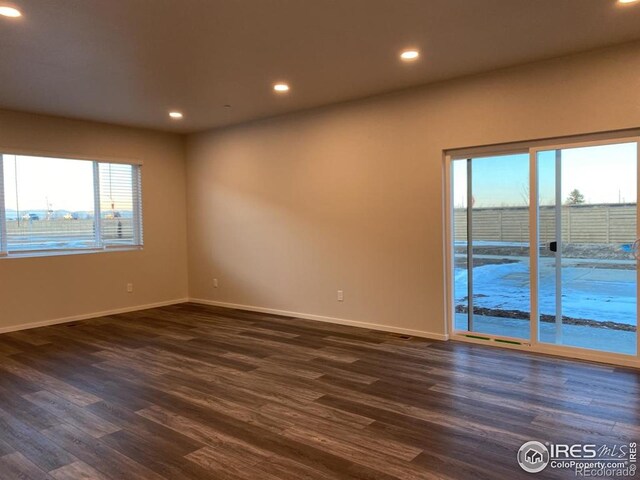 empty room featuring dark wood-type flooring, recessed lighting, and baseboards