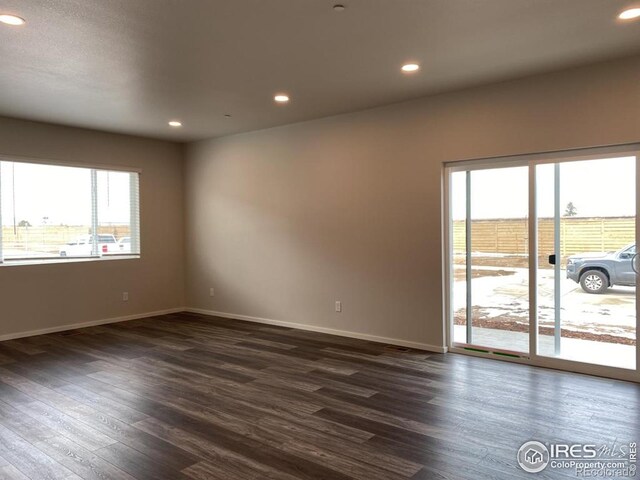 empty room featuring recessed lighting, baseboards, and dark wood-style floors