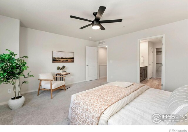 bedroom with connected bathroom, light colored carpet, baseboards, and visible vents