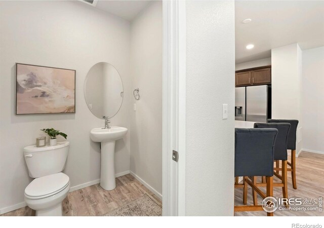 bathroom with baseboards, toilet, and wood finished floors