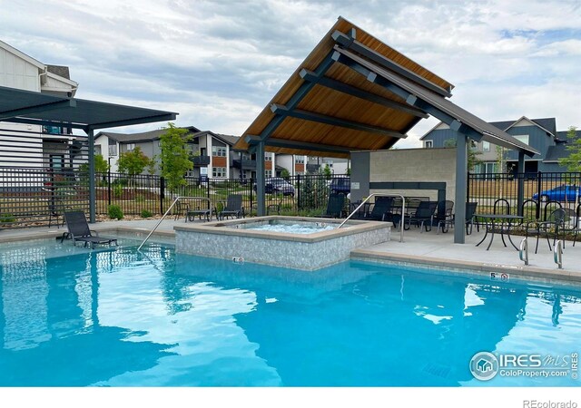 community pool featuring a patio, a hot tub, and fence