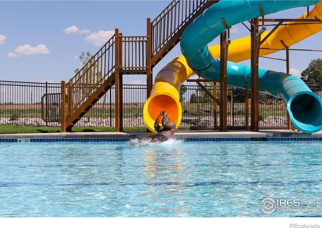 community pool with fence and a water slide