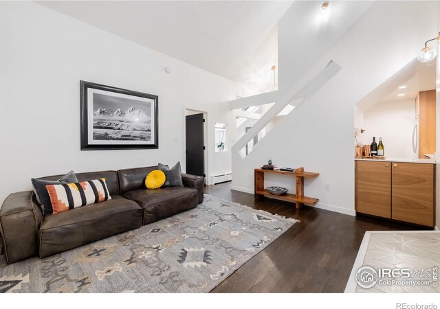 living room featuring stairway, baseboards, baseboard heating, and wood finished floors