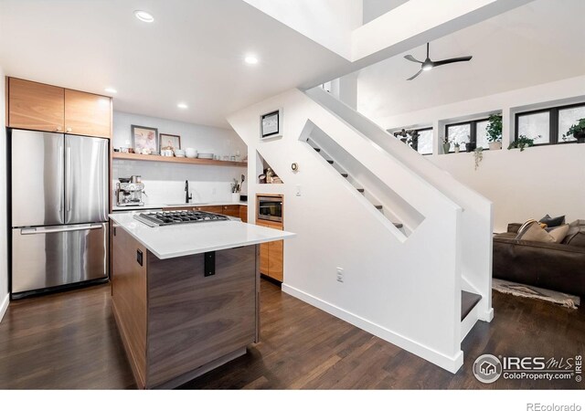 kitchen featuring a kitchen island, stainless steel appliances, dark wood-style floors, and light countertops