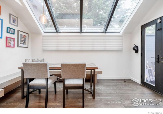 dining space with baseboards, french doors, wood finished floors, and vaulted ceiling with skylight