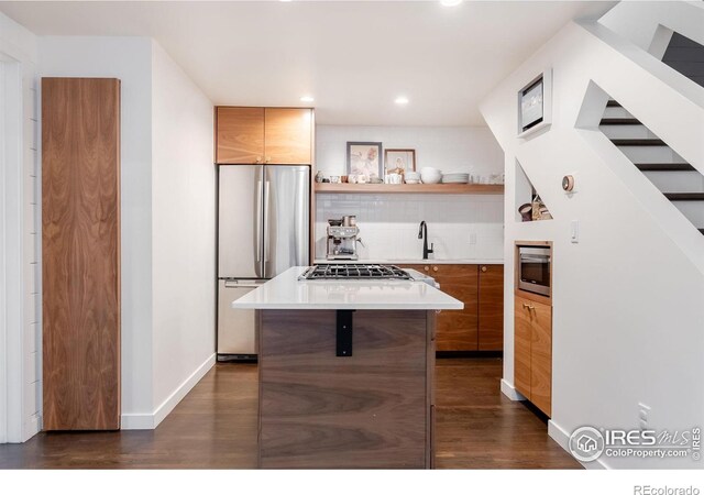 kitchen with backsplash, dark wood-style flooring, appliances with stainless steel finishes, and modern cabinets