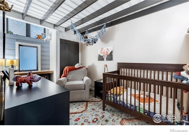 bedroom with a crib, a notable chandelier, and beamed ceiling