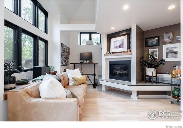 living area with light wood-type flooring, recessed lighting, a wealth of natural light, and a fireplace