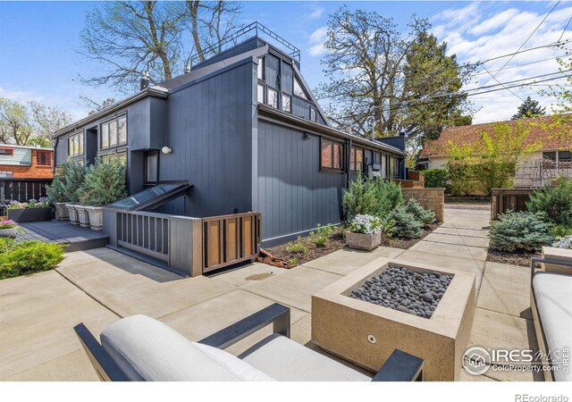 view of side of property featuring a patio and an outdoor living space with a fire pit