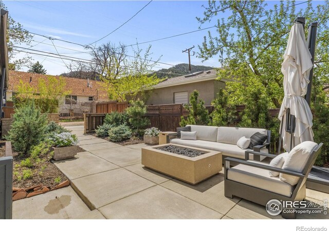 view of patio with an outdoor living space with a fire pit and fence