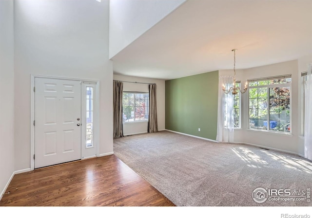 910 Pope Dr, Erie, CO 80516 - carpeted foyer featuring baseboards, a wealth of natural light, wood finished floors, and a notable chandelier