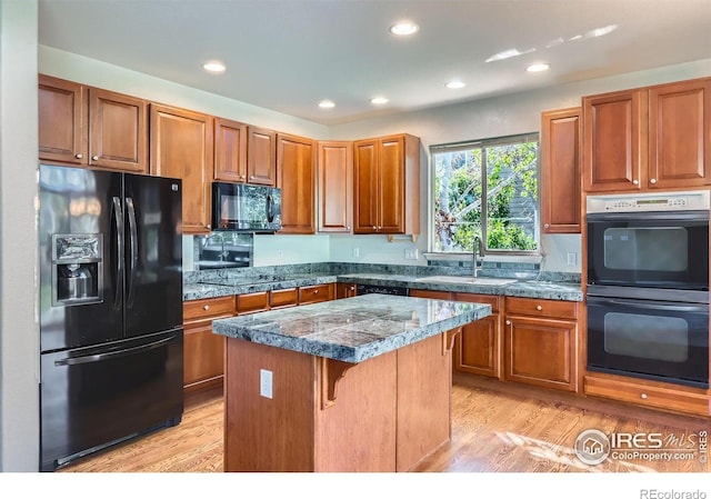 910 Pope Dr, Erie, CO 80516 - kitchen with a center island, a sink, black appliances, light wood finished floors, and tile counters