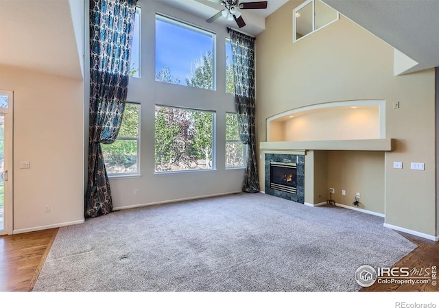 910 Pope Dr, Erie, CO 80516 - unfurnished living room featuring a towering ceiling, baseboards, a ceiling fan, carpet, and a premium fireplace