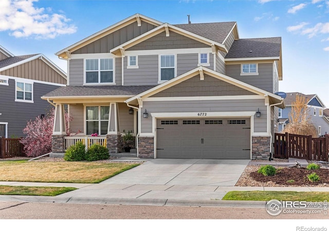 craftsman-style home with a porch, driveway, a garage, fence, and stone siding