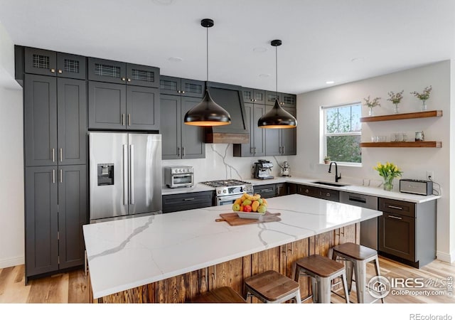 kitchen with light stone counters, a sink, light wood finished floors, and stainless steel appliances