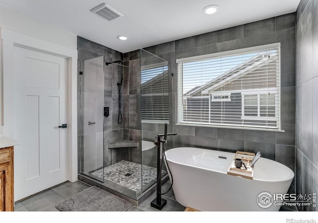 full bath featuring visible vents, a freestanding bath, tile walls, a shower stall, and wood finished floors