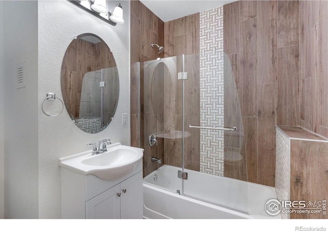 bathroom featuring vanity, enclosed tub / shower combo, and a textured wall