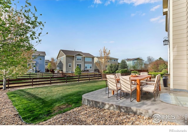 view of yard with a patio, fence, a residential view, and outdoor dining space