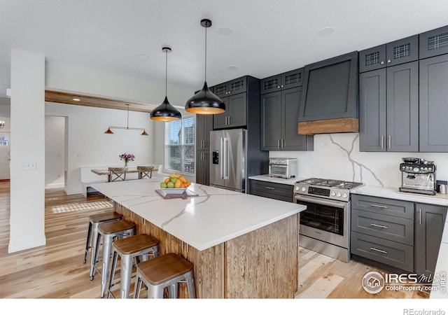 6772 Flintlock Rd, Timnath, CO 80547 - kitchen with stainless steel appliances, range hood, light wood finished floors, and a kitchen island