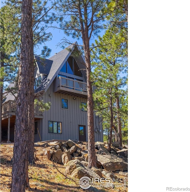 view of side of property with a balcony and roof with shingles