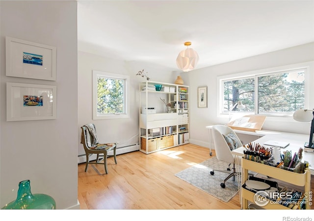 office area with wood finished floors, baseboard heating, and a healthy amount of sunlight