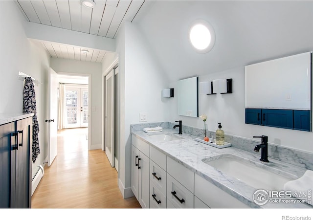 bathroom with a sink, baseboards, double vanity, and wood finished floors