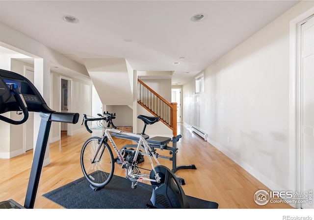 exercise area featuring recessed lighting, baseboards, a baseboard heating unit, and wood finished floors