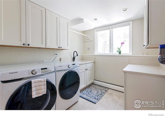 washroom featuring baseboard heating, washer and clothes dryer, a sink, cabinet space, and light tile patterned floors