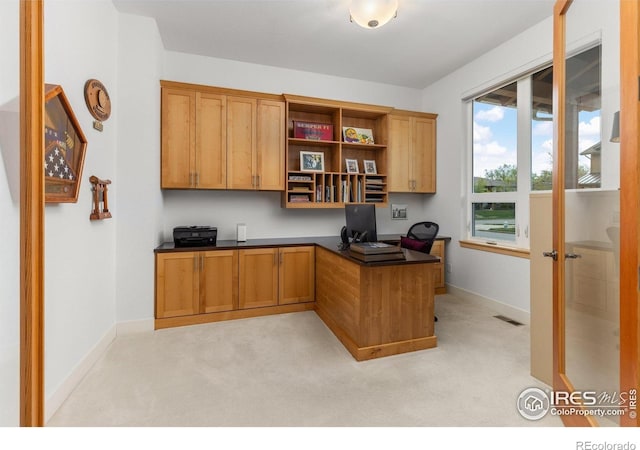 office space with baseboards, light carpet, and built in desk