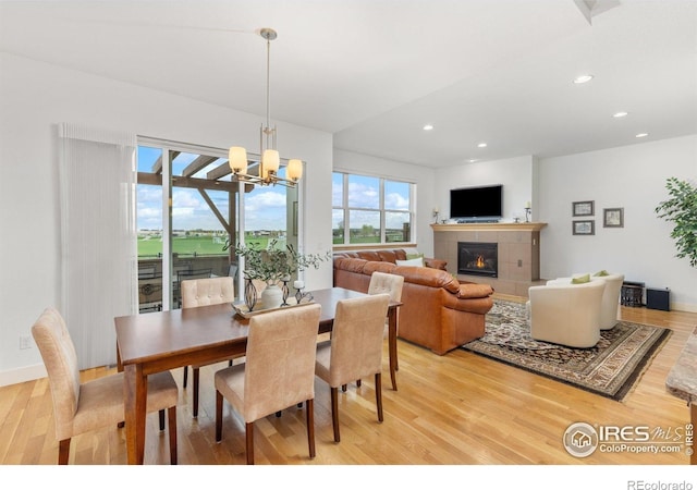 dining area with a tiled fireplace, recessed lighting, light wood finished floors, and a notable chandelier