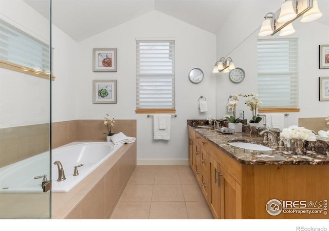 full bathroom featuring a garden tub, double vanity, baseboards, a sink, and vaulted ceiling