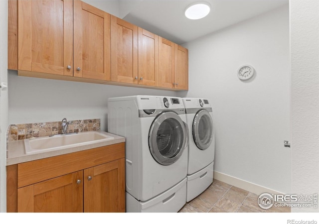 washroom featuring a sink, baseboards, cabinet space, and washer and dryer