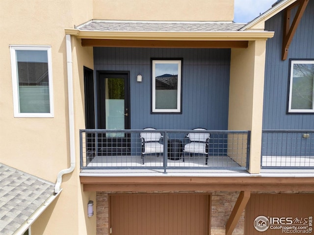 doorway to property with a garage, roof with shingles, stucco siding, and a balcony