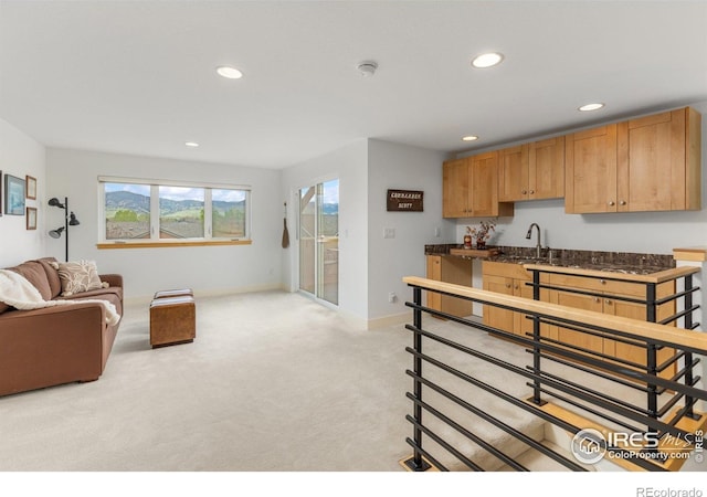 kitchen with light colored carpet, a sink, recessed lighting, baseboards, and open floor plan