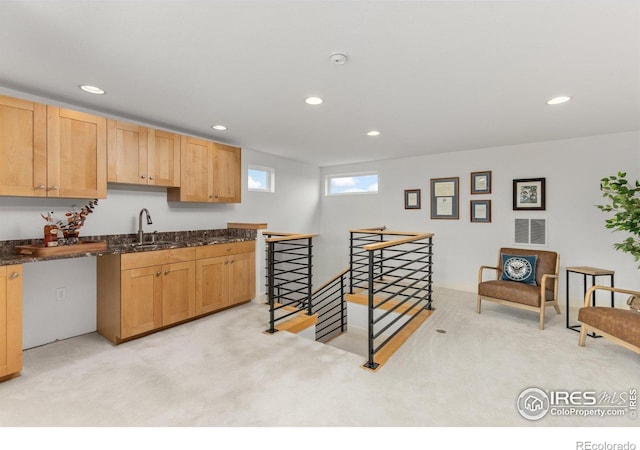 kitchen featuring visible vents, a sink, dark stone countertops, light carpet, and recessed lighting