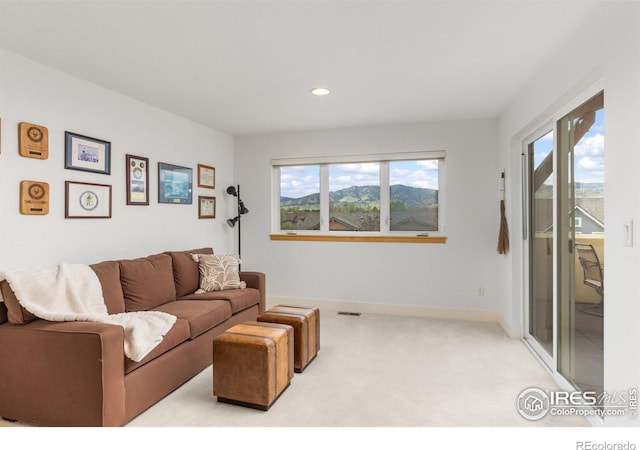living area featuring light colored carpet, baseboards, a healthy amount of sunlight, and visible vents