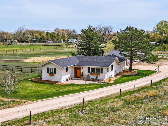 ranch-style home featuring fence, dirt driveway, a shingled roof, and a front lawn