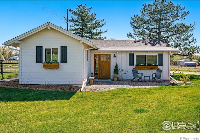ranch-style home with board and batten siding, fence, a shingled roof, and a front yard